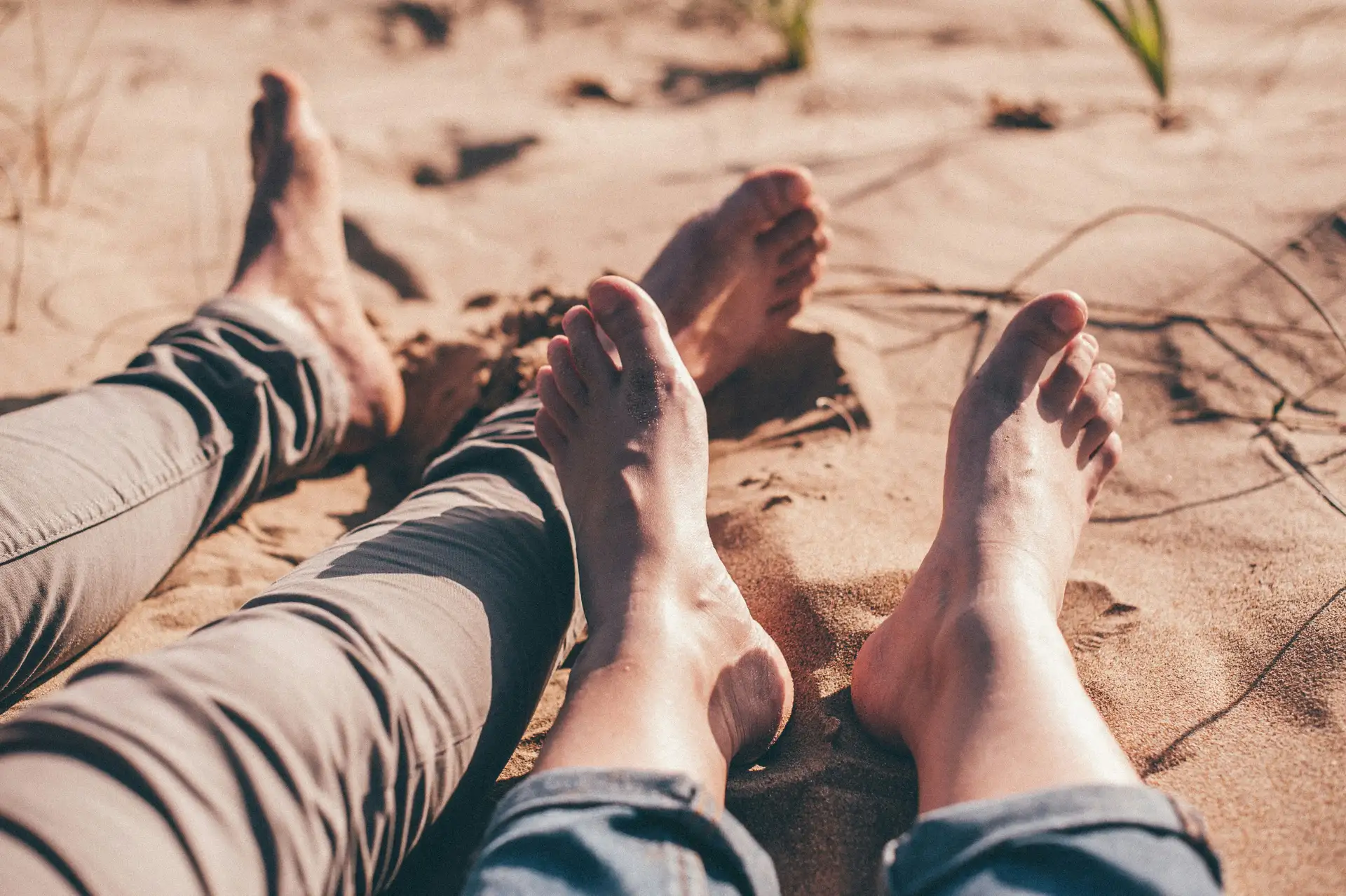 Twee paar blote voeten die ontspannen in het zand rusten